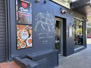 Fineline Painting artist hand painting a restaurant logo mural in Mona Vale